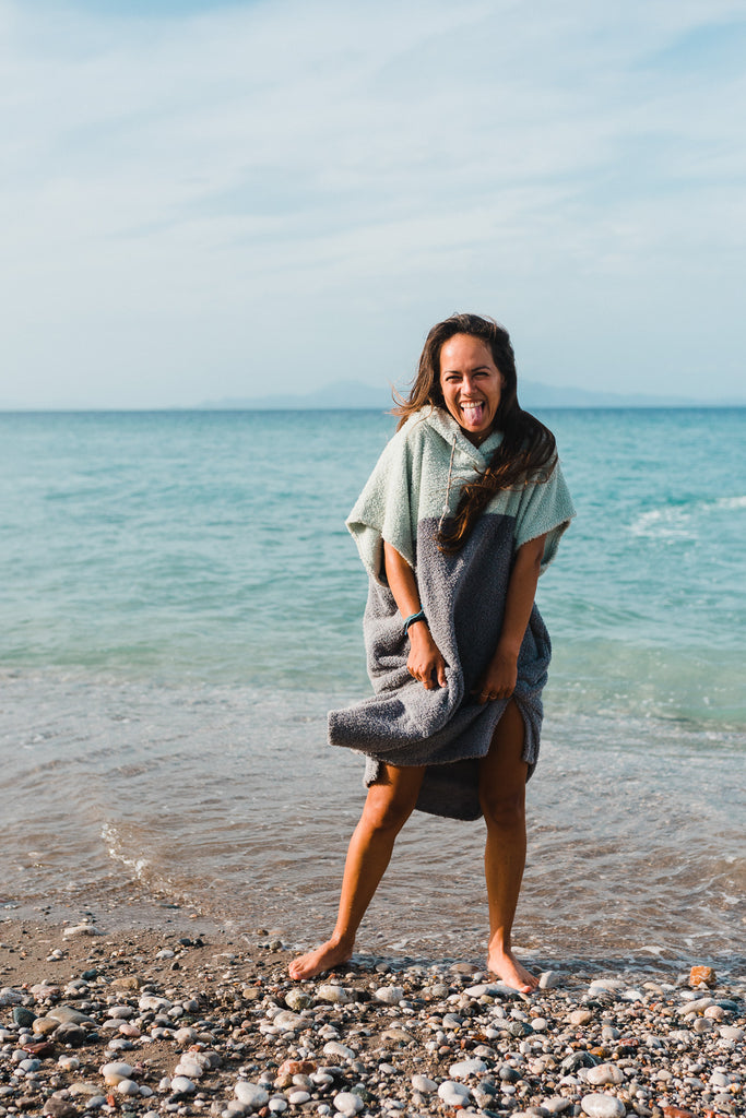 Frau am Strand trägt Surfponcho aus Baumwolle