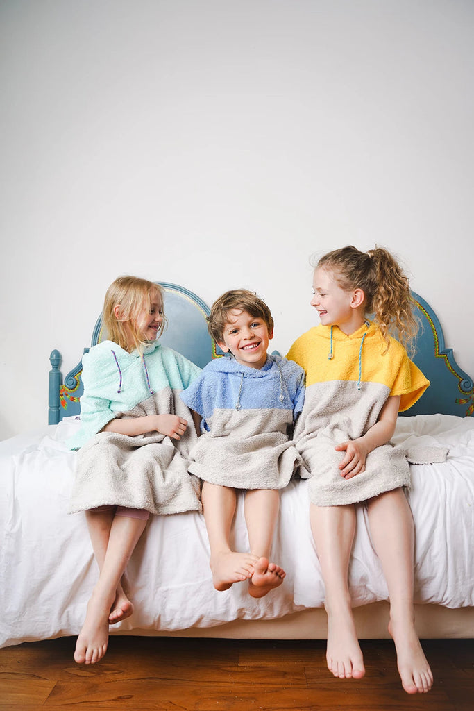 Kinder in bunten Badeponchos aus Baumwolle