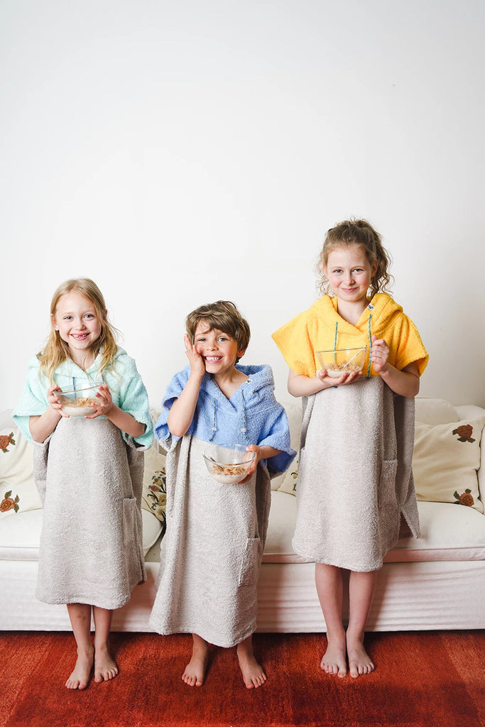 drei Kinder in bunten Badeponchos aus Baumwolle