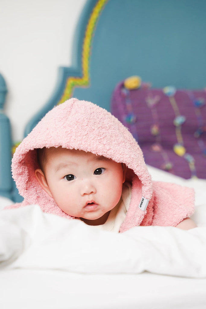 süsses asiatisches Baby mit rosa Badeponcho