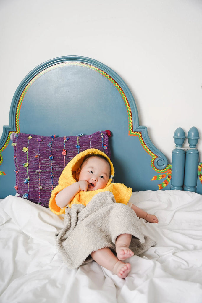 Baby im Bett liegend mit Badeponcho aus hochwertigem Frottee