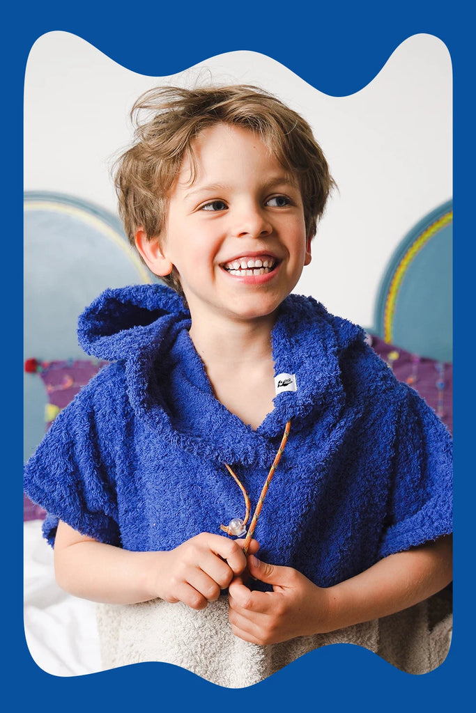 Kind trägt dunkelblauen Badeponcho aus Baumwolle