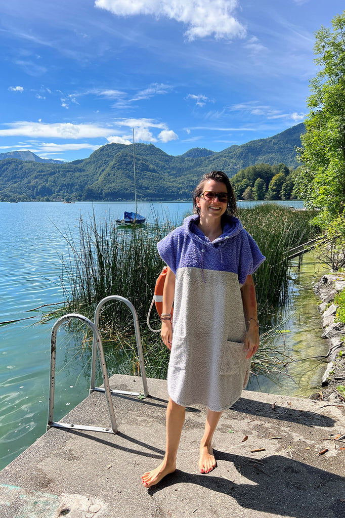 Dame trägt baumwoll Surfponcho am See im Badeurlaub