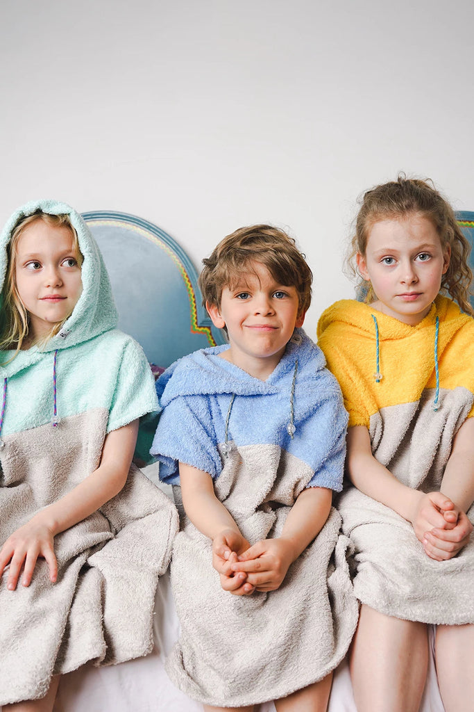 Kinder tragen bunte Badeponchos aus Baumwolle